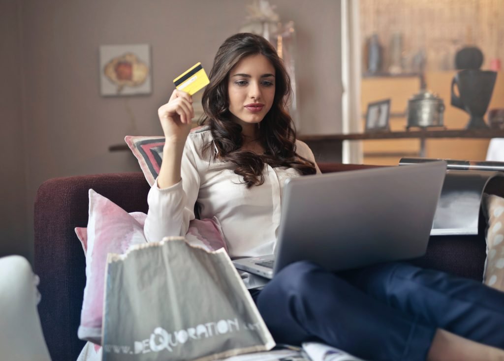Woman holding a credit card with a silver laptop